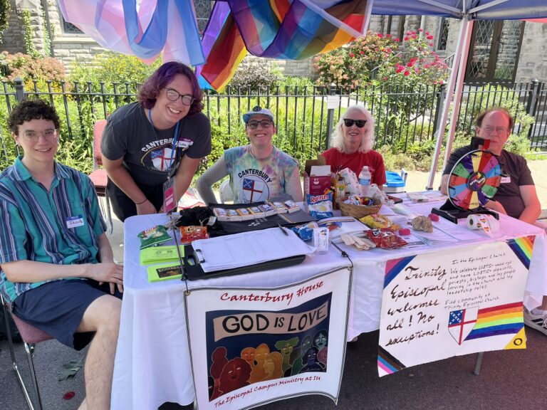 The morning shift of volunteers seated at a table covered with sway and welcome signs